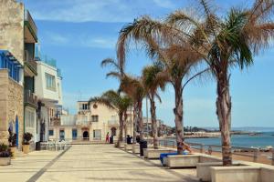 una pasarela con palmeras y una playa en Holiday Home Marina di ragusa, en Marina di Ragusa