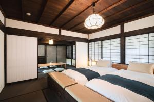 two beds in a room with windows and a table at Kiraku Obi in Nichinan