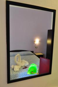 a mirror reflecting a bedroom with a bed with a swan toy at Bed & Breakfast Adriana in San Vito lo Capo