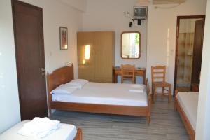 a bedroom with two beds and a table and chairs at Artemis Pension in Ios Chora