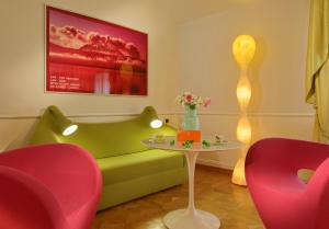 a living room with a green couch and two pink chairs at Byblos Art Hotel Villa Amistà in San Pietro in Cariano