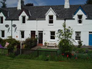 a white house with a bench in front of it at Crinan Canal Cottage in Lochgilphead