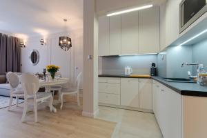 una cocina con armarios blancos y una mesa con sillas. en Apartamenty Gdańsk EU - Sopot Apartamenty, en Sopot