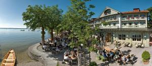 a group of people sitting outside of a building by the water at Hotel Seehof in Herrsching am Ammersee