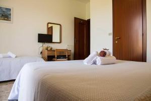 um quarto de hotel com duas camas com um urso de peluche sentado em cima em Hotel Silvia em Framura