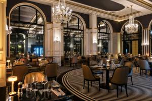 ラ・ボールにあるHôtel Barrière L'Hermitageのテーブルと椅子、シャンデリアのあるレストラン