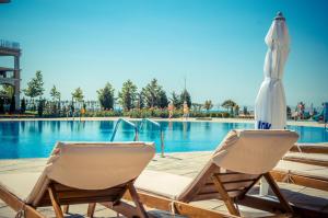 duas cadeiras e um guarda-sol junto a uma piscina em Prestige Sands Resort em Sunny Beach