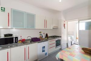 een keuken met witte kasten, een wastafel en een tafel bij Quinta da Torre in Câmara de Lobos