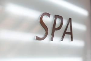 un panneau métallique qui dit spa sur un mur blanc dans l'établissement Best Western Les Bains Hotel et SPA, à Perros-Guirec