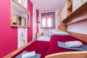 sypialnia z 2 łóżkami i czerwoną ścianą w obiekcie Kristina Apartments w mieście Zadar