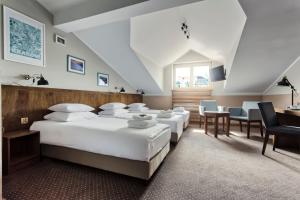 sypialnia z 4 łóżkami, stołem i krzesłami w obiekcie Daniel Griffin Aparthotel by Artery Hotels w Krakowie