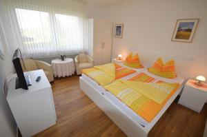 ein Schlafzimmer mit einem großen Bett mit gelben und orangefarbenen Kissen in der Unterkunft Haus Hannover in Carolinensiel