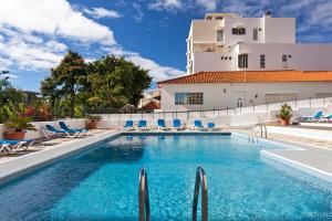 Una piscina con sillas y un edificio al fondo. en Casa Branca Apartments by TrIp2Portugal, en Funchal