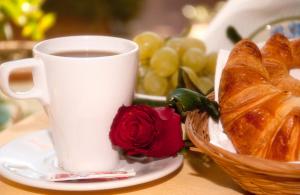 a cup of coffee and a basket of bread and a rose at B&B Villa San Leonardo in Mascali