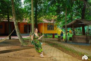 a woman in a green dress swinging on a rope swing at The Isle By Area 707 in Alwaye