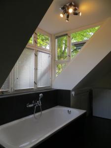 a large white bath tub in a bathroom with windows at Fischerhaus am See in Berlin