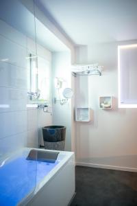 a white bathroom with a tub and a sink at The Originals Boutique, Hôtel Bulles by Forgeron, Lille Sud (Qualys-Hotel) in Seclin