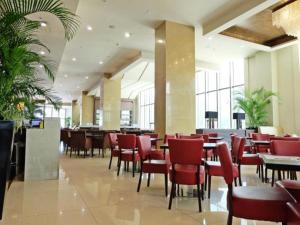 un restaurante con sillas rojas, mesas y ventanas en Mandarin Plaza Hotel, en Cebú