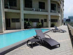 einen Pool mit zwei Liegestühlen neben einem Gebäude in der Unterkunft Mandarin Plaza Hotel in Cebu City