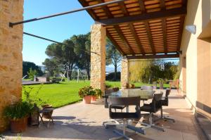 a patio with a table and chairs under a wooden pergola at Villa Esclanya in Begur