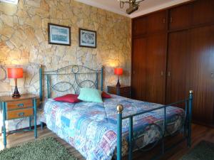 a bedroom with a bed and a stone wall at Casa da Ribeira (Sesimbra) in Sesimbra