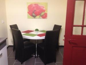 a dining room table with chairs and a red door at Die kleine Pension in Gößweinstein