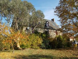 una casa vieja con árboles y arbustos delante de ella en Le Grand Pont en Estry