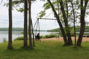 une personne assise sur une balançoire au bord d'un lac dans l'établissement Tally Ho Inn, à Huntsville