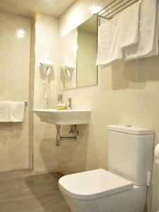 a white bathroom with a toilet and a sink at Hostal Paz in Gondomar