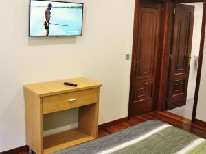 Habitación con TV en la pared y mesa. en Hostal Paz, en Gondomar