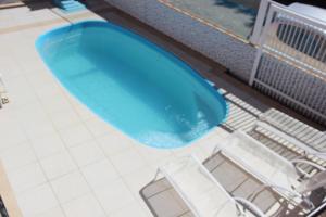 an overhead view of a blue swimming pool with chairs at Pousada da Guarda in Guarda do Embaú