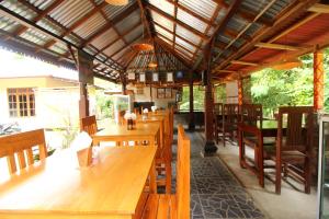 un restaurante con mesas de madera y sillas de madera en Edy Homestay, en Munduk