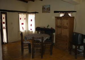 um quarto com uma mesa e cadeiras e uma televisão em Piedramora Tilcara em Tilcara