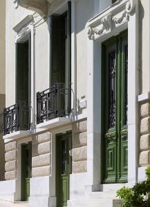 uma fachada de um edifício com portas e janelas verdes em Thiseio 1915 em Atenas