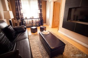 a living room with a black leather couch and a television at Alcam Arte Ciencia in Valencia