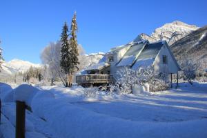 a house covered in snow with mountains in the background at Bear Paw Lodge in Golden