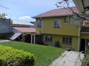 una casa amarilla con techo rojo en Habitacion Santo Domingo, Heredia, en Santo Domingo