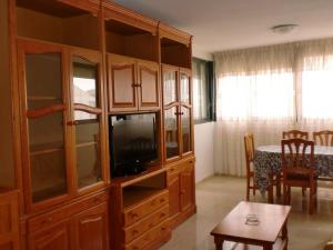 a living room with a large wooden cabinet with a tv at Kennedy 2 - Fincas Arena in Benidorm