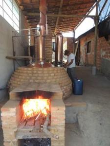 a man standing in front of a brick oven at Pousada Sitio da Serra in Carrancas