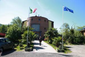 un hombre caminando por una calle con dos banderas en Hotel Il Canneto, en Porto Ceresio