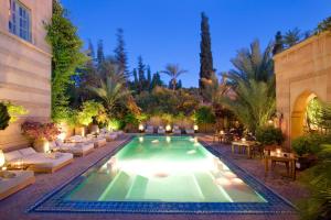 馬拉喀什的住宿－瑞茲蘭德博宮酒店及SPA，庭院内一个带沙发和桌子的游泳池