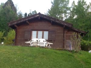 a house with two white chairs in front of it at Le bois ramé in Neuvecelle