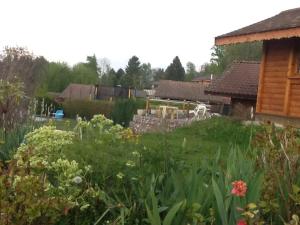 a garden with green grass and flowers in front of a house at Le bois ramé in Neuvecelle