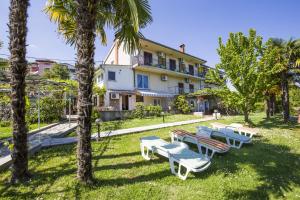 a group of picnic tables and palm trees in front of a building at Apartments & Rooms Ribarić in Lovran