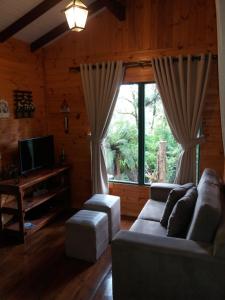 a living room with a couch and a large window at Cabana Costa Rural in Gramado
