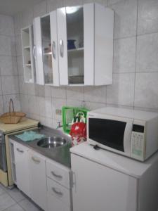 a kitchen with a microwave and a sink at Kitinete Em Matinhos Com Piscina in Matinhos