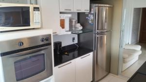 a kitchen with a stainless steel refrigerator and a microwave at Barramares Flat in Rio de Janeiro