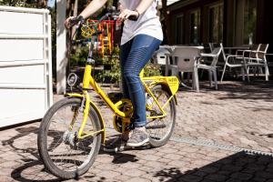 a woman riding a yellow bike on a street at Hotel Orsa Maggiore in Milano Marittima