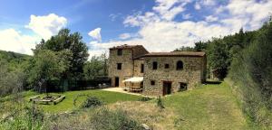 セッジャーノにあるLe Case Della Buca Agriturismo ed Agricampeggioの草原の古石造りの家
