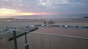 a view of a beach and the ocean at sunset at lounge appartement zeedijk Oostende in Ostend